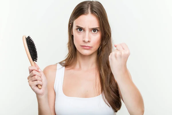 Genç Beyaz Kadın Kameraya Yumruk Gösteren Bir Saç Fırçası Tutan — Stok fotoğraf
