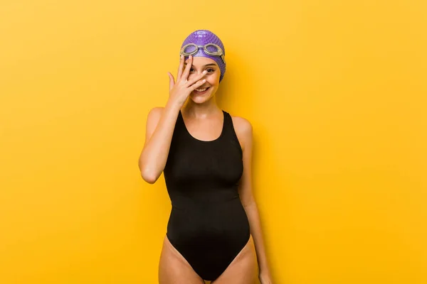 年轻的游泳白种女人通过手指在相机眨眼 尴尬地遮住脸 — 图库照片