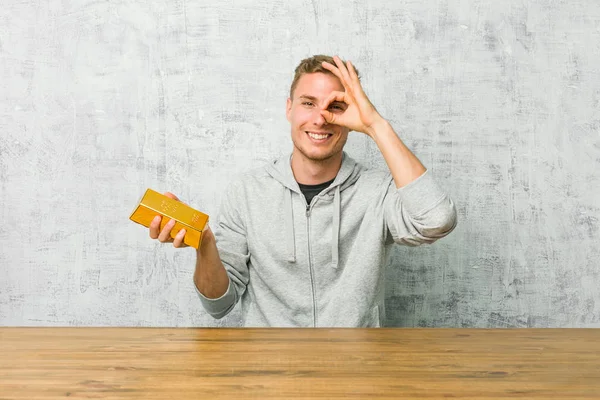 Young Handsome Man Holding Gold Ingot Table Showing Okay Sign — Stock Photo, Image