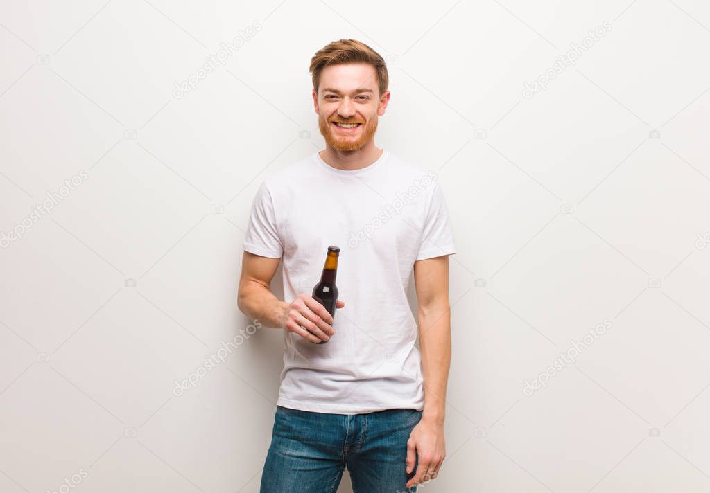 Young redhead man cheerful with a big smile. Holding a beer.