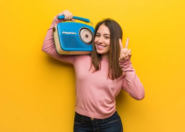 Young cute woman holding a vintage radio showing number two