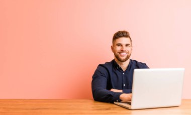 Young man working with his laptop happy, smiling and cheerful.
