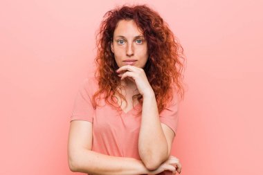 Young natural and authentic redhead woman smiling happy and confident, touching chin with hand.