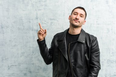 Genç rockçı gülümseyerek işaret parmağıyla işaret ediyor..