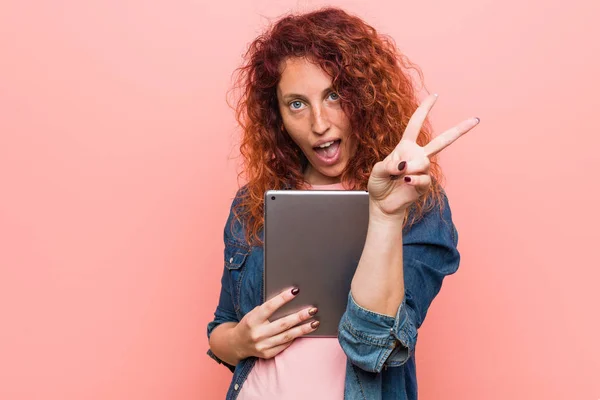 Young Caucasian Redhead Woman Holding Tablet Showing Number Two Fingers — Stok fotoğraf