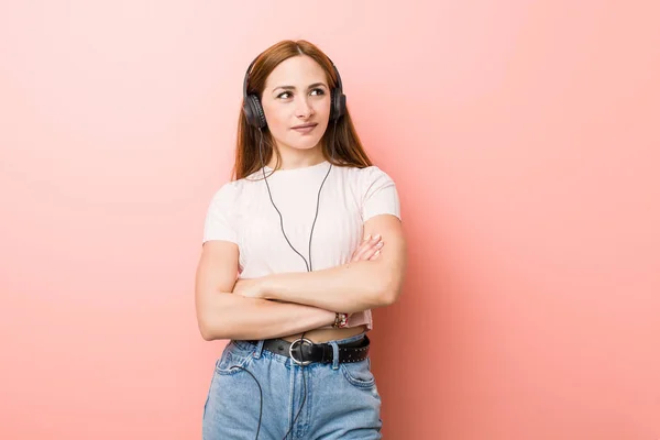 Young caucasian woman listen to music smiling confident with crossed arms.