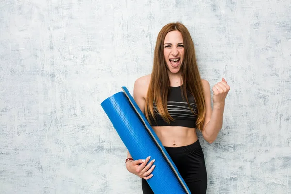 Young Caucasian Sportswoman Holding Mat Cheering Carefree Excited Victory Concept — Stok fotoğraf