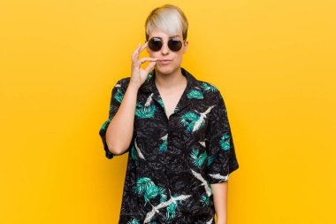 Young curvy woman wearing a summer look with fingers on lips keeping a secret.