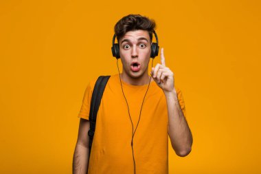 Kulaklıklı müzik dinleyen genç havalı öğrenci rahatlamış fotokopi odasına bakan bir şey düşünüyor..