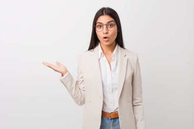 Beyaz bir arkaplanda izole edilmiş genç bir Arap kadın avuç içi fotokopi alanını elinde tutmaktan etkilenmiş..