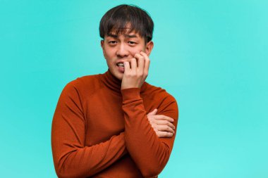 Tırnak yiyen genç Çinli adam, gergin ve çok endişeli.