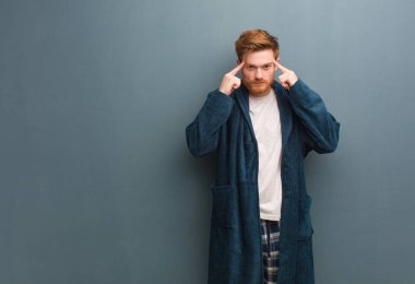 Pijamalı genç kızıl adam konsantrasyon jesti yapıyor.