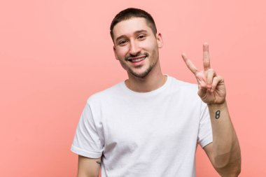 İki numarayı parmaklarıyla gösteren sıradan bir genç..