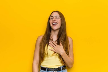 Kızıl saçlı genç kadın çilsiz gülüyor ve elini göğsüne koyuyor..