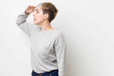 Beyaz arka planda izole edilmiş, elini alnına koyan genç, beyaz bir kadın..