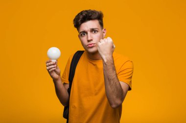 Genç bir öğrenci elinde bir ampul tutuyor. Parmağıyla bir numarayı gösteriyor..