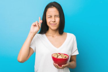 Mısır gevreği kasesi tutan genç İspanyol kadın şans getirsin diye dua ediyor.