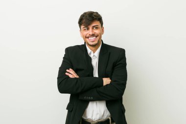 Genç iş adamı kollarını kavuşturarak gülümsüyor..