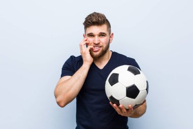 Elinde futbol topu tutan, tırnaklarını yiyen, gergin ve endişeli bir beyaz adam..