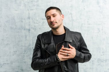 Genç rockçı dostça bir ifadeye sahiptir, avuçlarını göğsüne bastırır. Aşk konsepti.