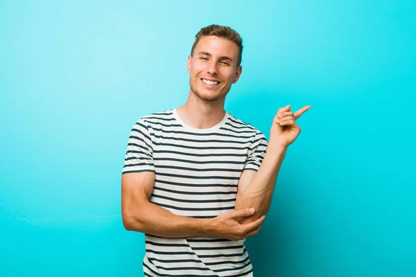 Young Caucasian Man Blue Wall Smiling Cheerfully Pointing Forefinger Away — ストック写真