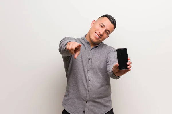 Jovem Latino Segurando Telefone Alegre Sorrindo Apontando Para Frente — Fotografia de Stock