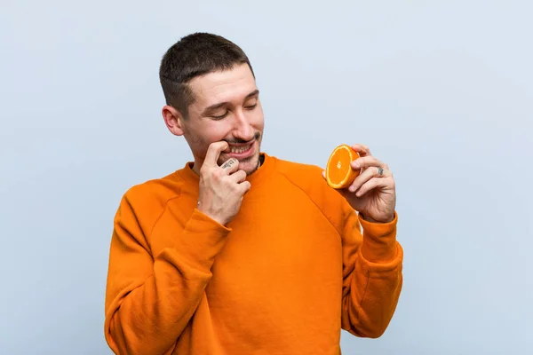 Joven Hombre Caucásico Sosteniendo Una Naranja Relajado Pensando Algo Mirando — Foto de Stock
