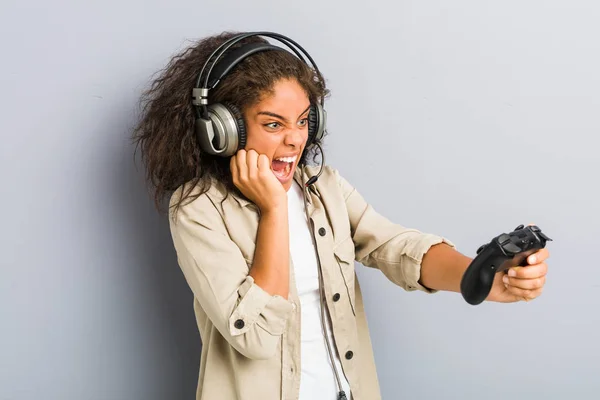 ヘッドフォンとゲームコントローラを使用して若いアフリカ系アメリカ人女性 — ストック写真