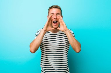 Mavi duvarın karşısında genç beyaz bir adam heyecanlı bir şekilde bağırıyor..