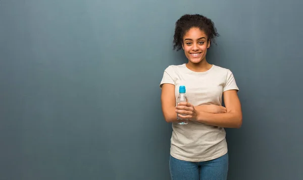 Молодая Черная Женщина Скрещивает Руки Улыбается Расслабляется Держит Бутылку Водой — стоковое фото