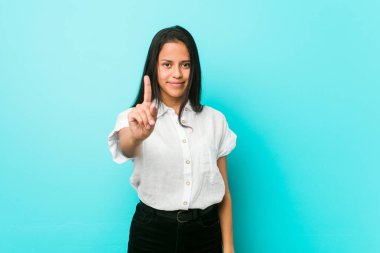 Mavi duvara yaslanmış genç İspanyol havalı kadın parmaklarıyla bir numarayı gösteriyor..