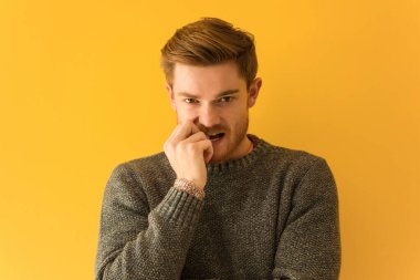 Genç kızıl saçlı adam yakından tırnak yiyor, gergin ve endişeli.