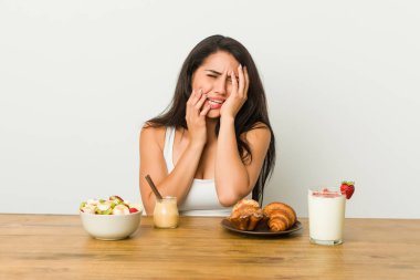 Genç, kıvrımlı bir kadın kahvaltı yapıyor sızlanıyor ve ağlıyor..