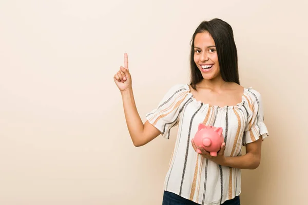 Joven Mujer Hispana Sosteniendo Una Alcancía Sonriendo Alegremente Señalando Con — Foto de Stock