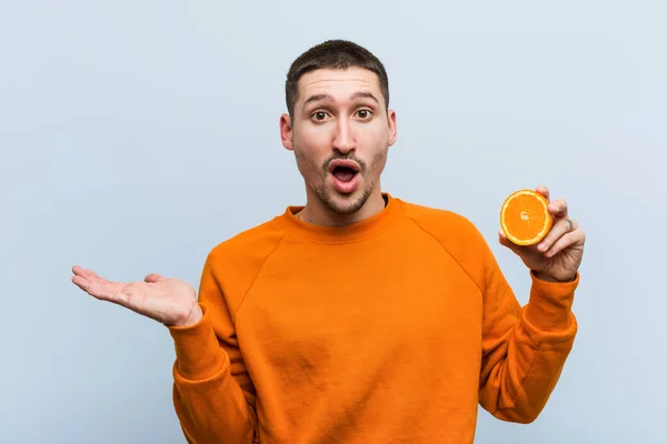 Joven Hombre Caucásico Sosteniendo Espacio Copia Impresa Naranja Palma — Foto de Stock