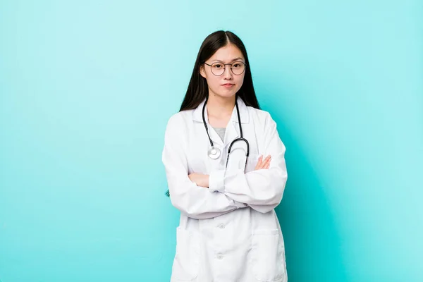 Young chinese doctor woman unhappy looking in camera with sarcastic expression.