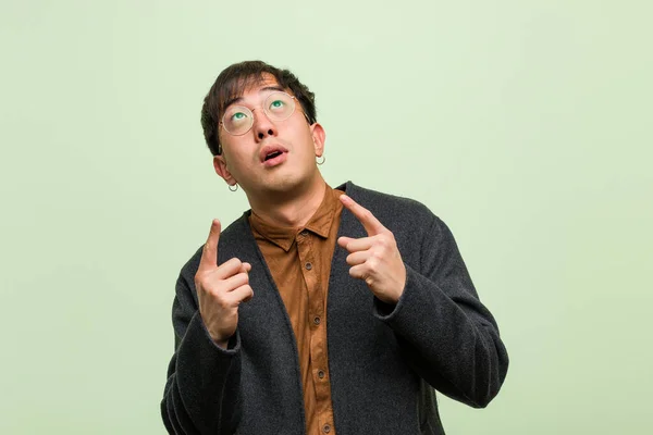 Homem chinês jovem contra uma parede verde — Fotografia de Stock