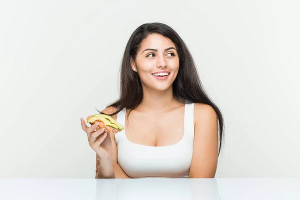 Young Hispanic Woman Holding Avocado Toast Smiling Confident Crossed Arms — Stock Photo, Image