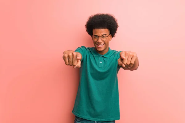 年轻的非洲裔美国人快乐地穿过粉红的墙壁 微笑着指向前方 — 图库照片
