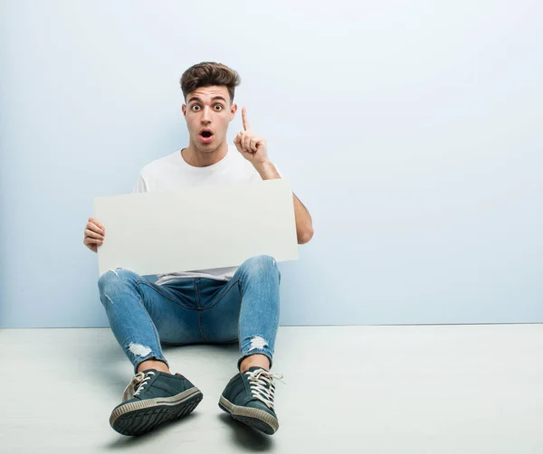 Young Man Holding Placard Sitting His Home Floor Having Some — Stock Photo, Image