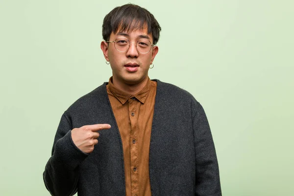 Mladý čínský muž proti zelené stěně — Stock fotografie