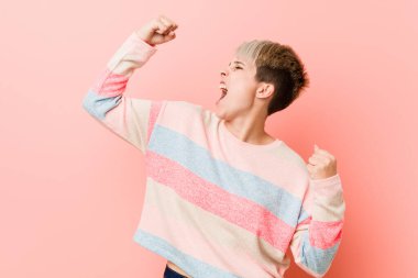 Genç doğal kıvrımlı kadın zaferden sonra yumruğunu kaldırıyor, kazanan konsept.