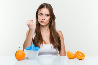 Kameraya yumruğunu gösteren portakal sıkacağı olan beyaz bir kadın, agresif bir yüz ifadesi..