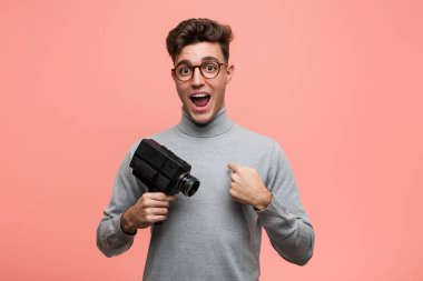 Elinde bir film kamerası olan genç entelektüel adam kendini gösterirken şaşırdı ve gülümsedi..