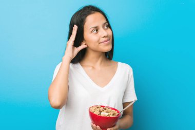 Genç İspanyol kadın elinde mısır gevreği kasesiyle bir dedikoduyu dinlemeye çalışıyor..