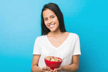 Genç İspanyol kadın elinde mısır gevreği kasesiyle mutlu, güler yüzlü ve neşeli.