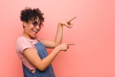 Young mixed african american teenager woman excited pointing with forefingers away. clipart