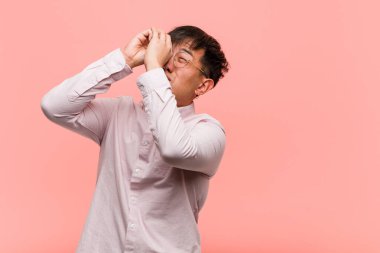 Genç Çinli adam dürbün hareketi yapıyor.