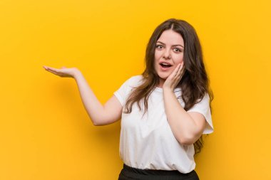 Genç kıvrımlı ve cüsseli bir kadın avuç içinde fotokopi alanı tutuyor, el üstünde tutuyor. Şaşırmış ve mutlu..