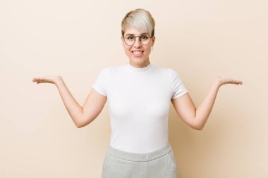 Beyaz gömlek giyen genç, otantik, doğal bir kadın kollarıyla terazi yapıyor, mutlu ve kendinden emin hissediyor..